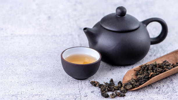 heißer tee in schwarzer teekanne und tassen und trockene teeblätter über hellgrauem zementhintergrund. - chinese tea stock-fotos und bilder