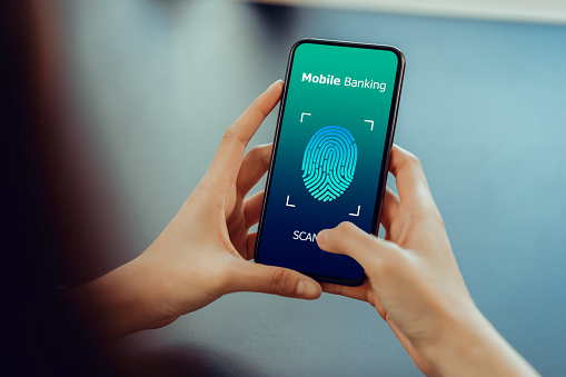 Hands holding smartphone and show the fingerprint scanner screen to access online banking.\