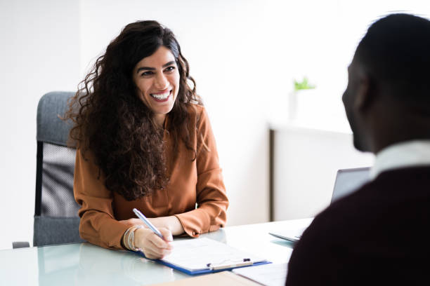 Female Manager Interviewing A Male Applicant Female Manager Interviewing A Young Male Applicant In Office recruiter photos stock pictures, royalty-free photos & images
