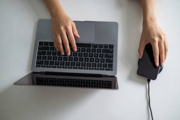 istock Young woman charge her phone with wireless charger while working with laptop 1226521638