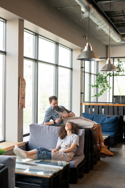istock Two young exhausted waiters in workwear relaxing on couches in cafe 1226530305