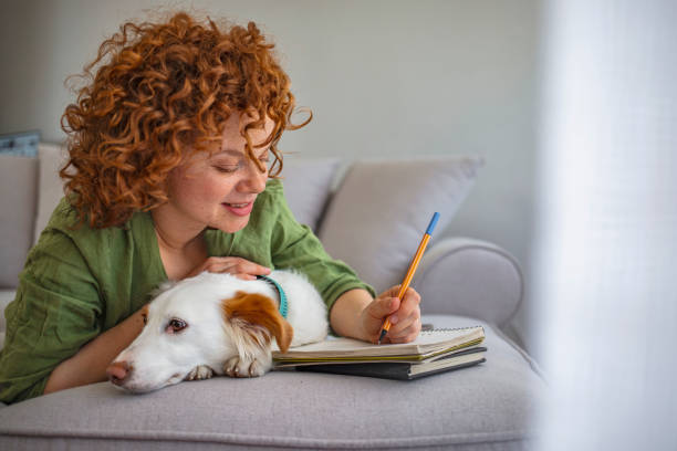 istock A girl writes in a notebook and plays with a dog. 1226531213