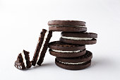 Closeup of pieces of broken sandwich cookie and stack of dark double cookies with filling