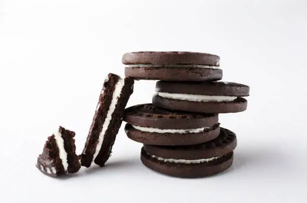 Closeup of stack of dark sandwich cookies and broken on the white background.Vertical image