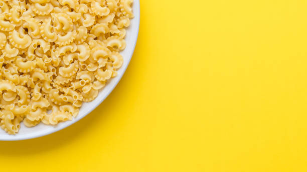istock many dry unprepared pasta - cockerels on a beige plate on a yellow background, copy space for text 1226537303