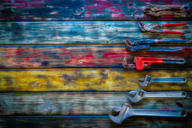 Aged construction hand tools inventory pliers nippers, wrenches, grip, pipe wrench organized in a row on vintage grunge colorful wooden background