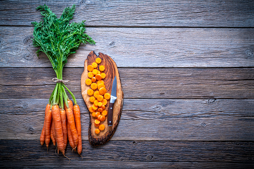 Carrots bunch fresh on cutting board with slices over wooden rustic wood board background