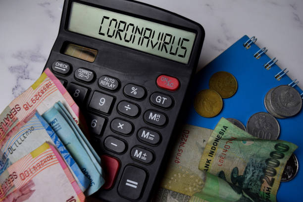 istock Coronavirus write on the calculator and rupiah banknotes on Office Desk. 1226544897