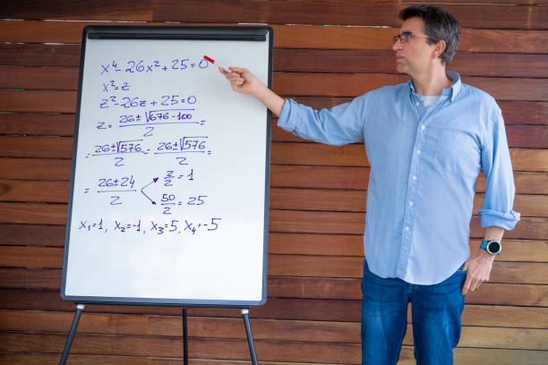 istock Male teacher teaching maths on white board pointing equation on wooden background 1226546161
