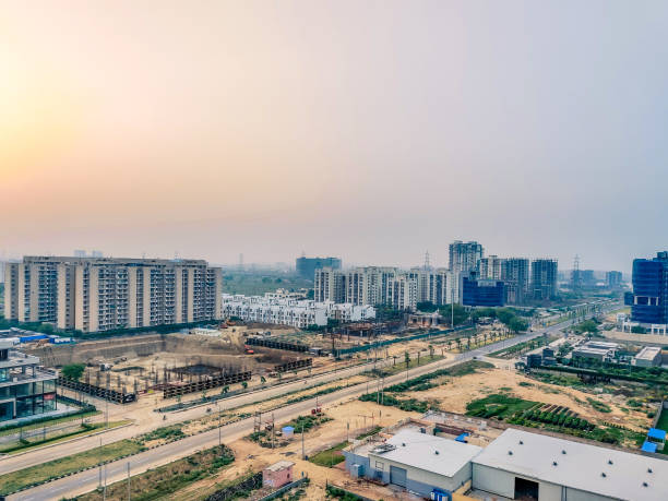 disparo de paisaje aéreo que muestra paisaje de gurgaon con luz solar y nubes al atardecer, edificios inacabados en construcción y rascacielos a lo lejos - lucknow fotografías e imágenes de stock