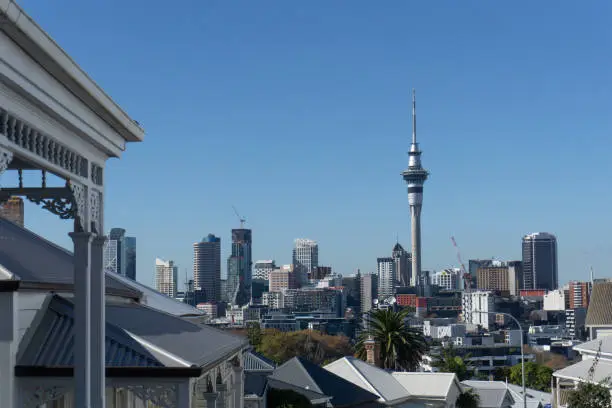 Auckland New Zealand - May 22 2020; City central business district and landmark Skytower in distance viewed from Ponsonby across roof tops of villa homes in foreground.