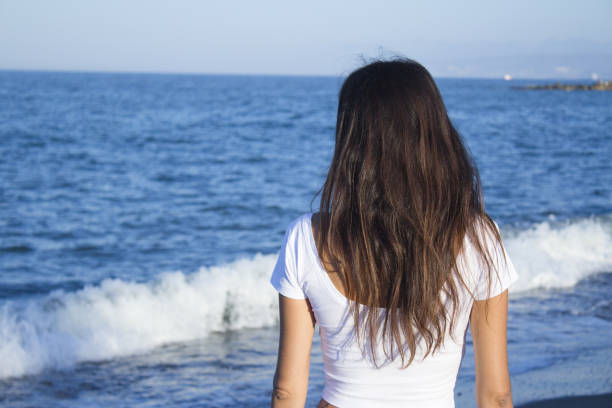 istock Girl dressed in white with the sea on her back. Tranquil scene 1226549738