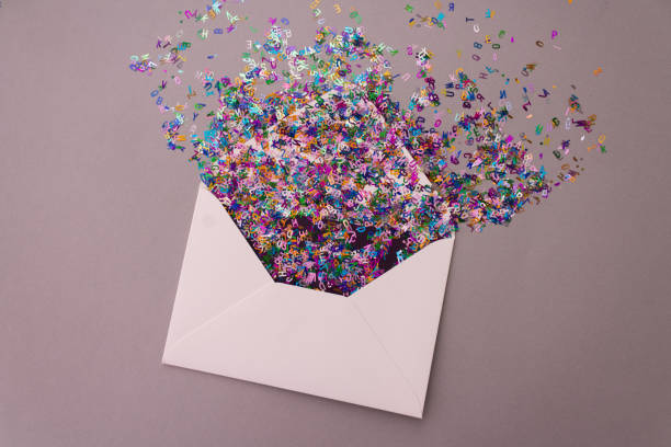 istock Opened white envelope with multicolored sparkle glitter confetti letters on pastel lilac background. Festive greeting concept. Flat lay style. Top view 1226551856
