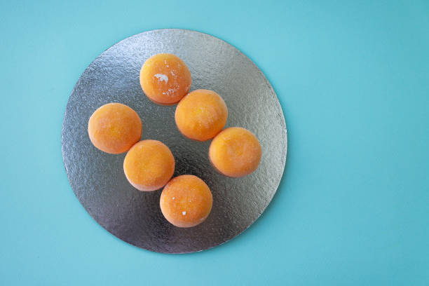 Mochi with mango. Premium ice-cream wrapped in sweet rice dough, traditional japonese desert. Gluten Free. Orange on pastel blue