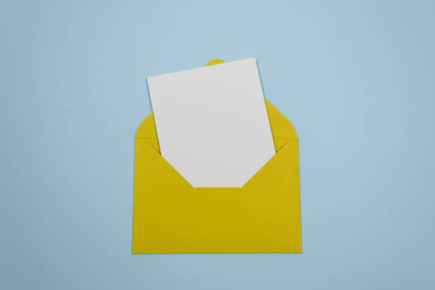 istock Minimalistic composition with a beautiful festive yellow mustard envelope, white blank card on a trendy blue pastel background. Mockup with envelope and blank card. Place for text. Flat lay. Top view 1226551926