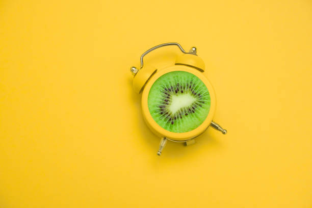 istock flat lay creative art collage alarm clock with kiwi fruit on a yellow  background 1226553068