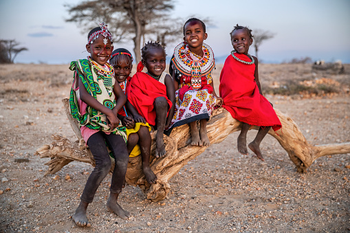 Group of happy African little children from Samburu tribe sitting on tree trunk, Kenya, Africa. Samburu tribe is north-central Kenya, and they are related to  the Maasai.