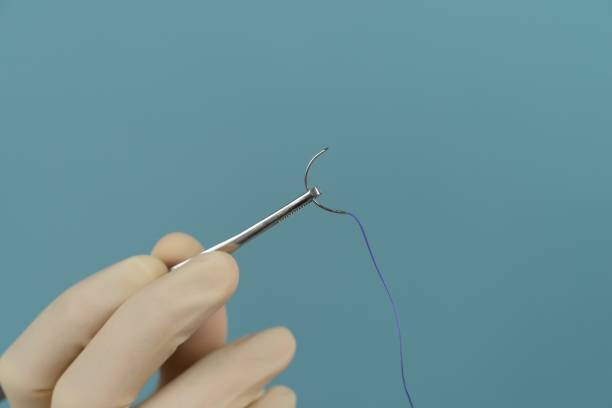 istock doctor holds a surgical thread with a needle in gloves with a mask on a blue background 1226557523