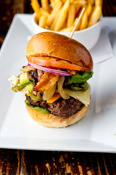 istock Bacon cheeseburger. Classic American style Burger with two patties, crispy Bacon, melted Swiss cheese, caramelized onions on a toasted brioche and served with crispy French fries. Bar favorite. 1226560441