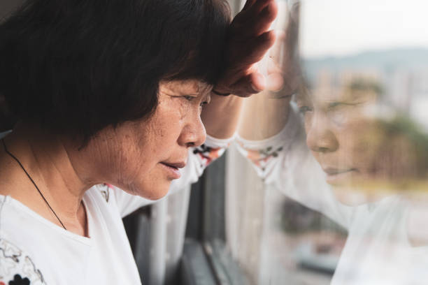 istock Worried senior woman by window 1226560694