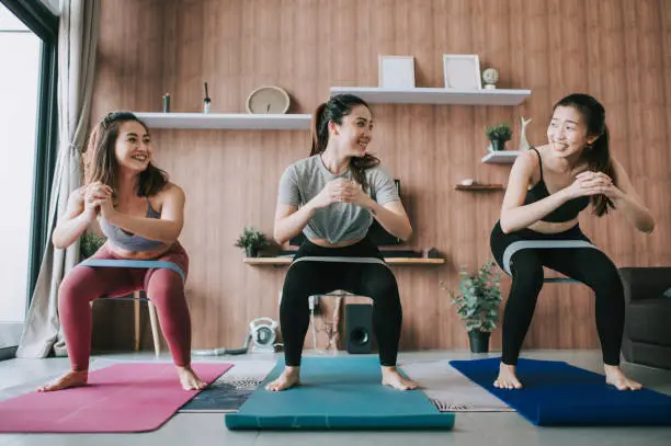 Photo of a group of asian chinese female friends practicing yoga in domestic living room together