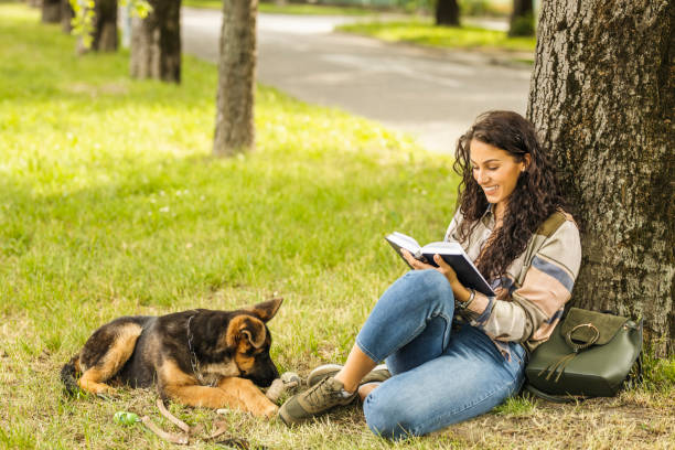 istock Student reading book near her dog at the park 1226561936