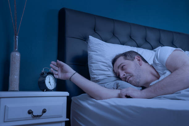 istock sleepless man looks at his alarm clock at night 1226563309
