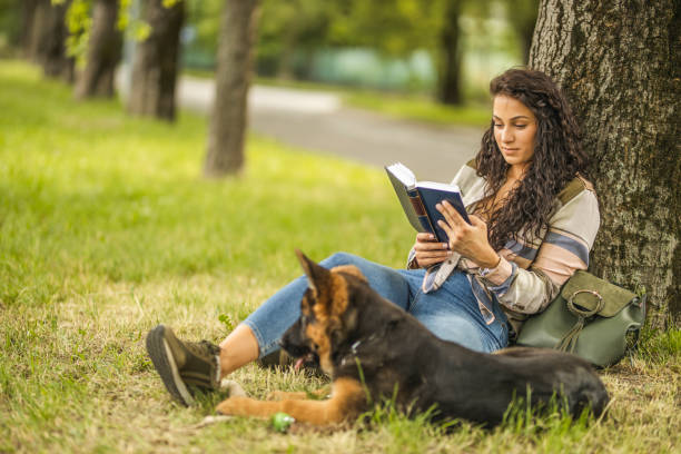istock Student reading book near her dog at the park 1226563358
