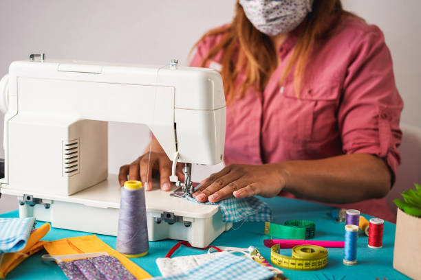 istock Woman worker sewing trendy face masks during coronavirus outbreak - Home made diy protective mask against virus - Focus on left hand 1226565426