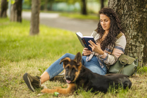 istock Student reading book near her dog at the park 1226565926