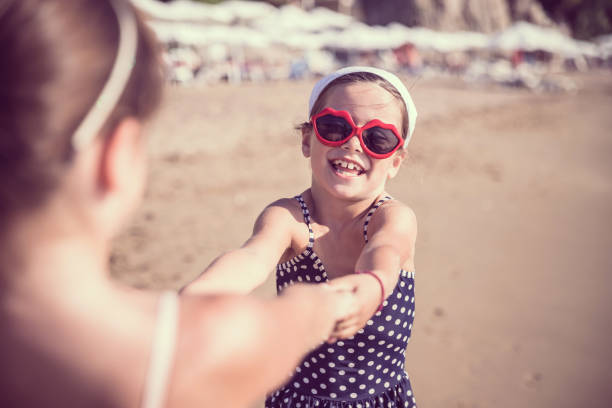 Baby girl and baby boy kissing on the beach in straw hats.