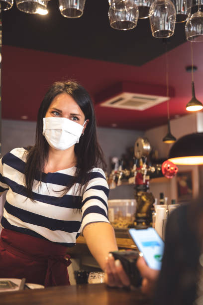 istock Woman in a cafe bar paying using contactless payment 1226568533