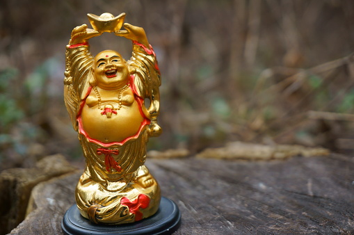 Buddha statue on a wooden background. Symbol of wealth and abundance. Feng Shui.
