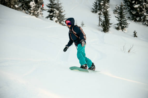 istock Female snowboarder riding down the mountain snowcovered slope 1226572779