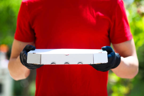 istock A man hands rubber gloves with a box pizza. 1226577005