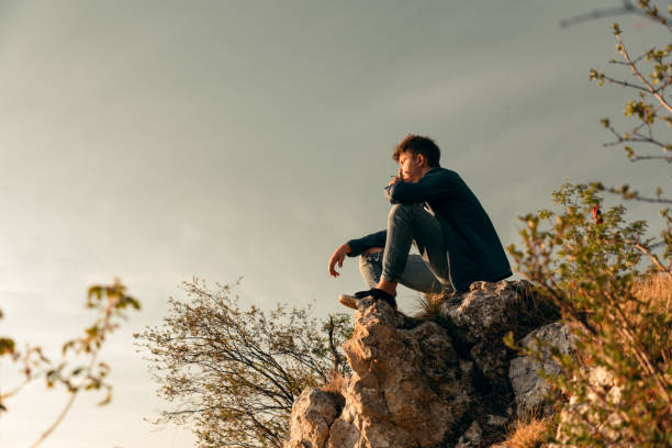istock Young Man Sitting on the Top of a Rock 1226578400