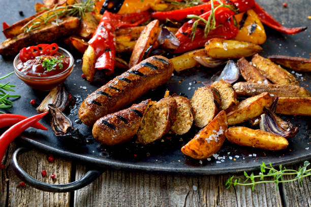 Vegan grill meal Grilled vegan sausages with hot sauce, potato wedges and vegetables meat substitute stock pictures, royalty-free photos & images