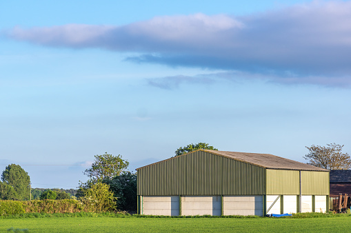 Prefabricated farm building in a rural setting on a sunny day with blue sky.