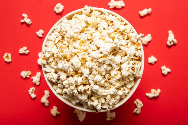 istock Tasty popcorn in a paper cup on a red background, top view 1226582542