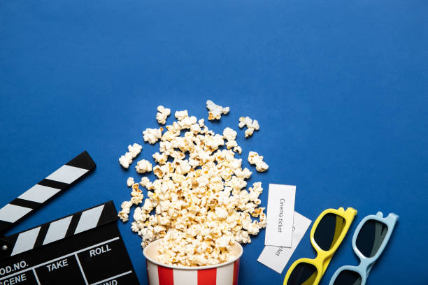 istock Paper cup with popcorn and movie clapper on a blue background, place for text 1226582628