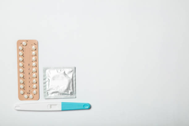 pilules contraceptives féminines, test de grossesse et préservatif sur fond blanc - contraceptive sex education birth control pill condom photos et images de collection