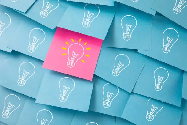 Many light bulbs drawn on blue and pink adhesive notes