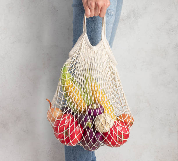 istock young woman holding a reusable mesh bag with fresh vegetables. zero waste concept. 1226584116