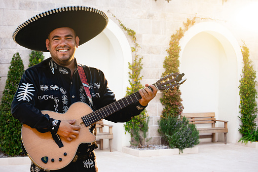 Portrait of a traditional mariachi holding Mexican flag outdoors