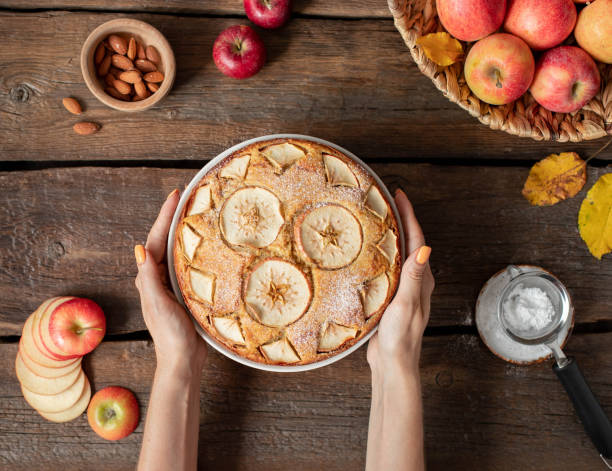istock female hands hold apple pie with powdered sugar, top view 1226584245