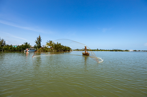 Hoi An, Quang Nam, Vietnam: December 13, 2019: A traditional Fisherman is fishing in a river at Hoi An in Vietnam