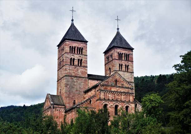 steeples of murbach abbey looming out of the forest in the vosges - murbach imagens e fotografias de stock