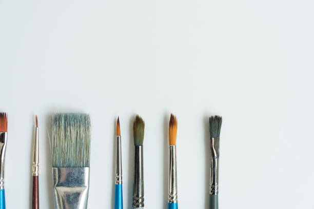 istock At the bottom, on a clean white sheet, there are brushes for drawing with paints. Brushes of different shapes and sizes. Postcard, background, texture. Space for text. The view from the top. 1226592446