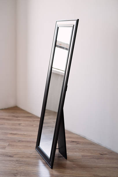 istock a rectangular mirror in a brown wooden frame stands indoors on a white background, the mirror is in an empty room 1226595714