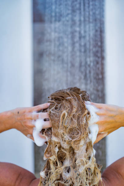 Close-up young woman washing hair with shampoo rear view of young blond woman washing hair with shampoo. Close-up washing hair stock pictures, royalty-free photos & images